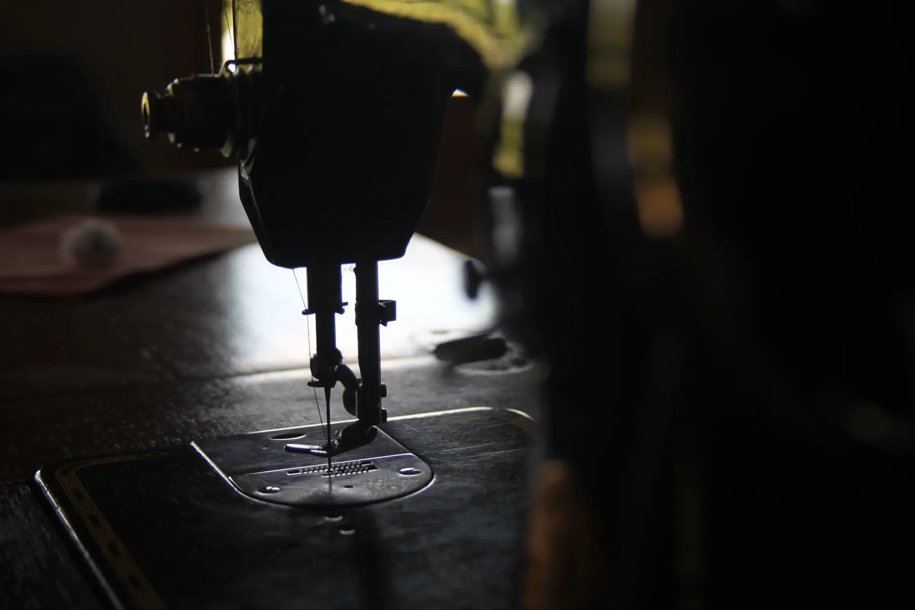 An industrial sewing machine under a work lamp